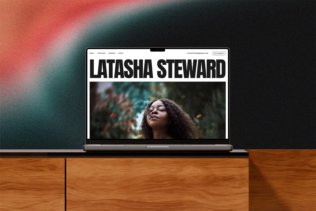 A MacBook on a wooden table showcasing Latasha Steward Website
