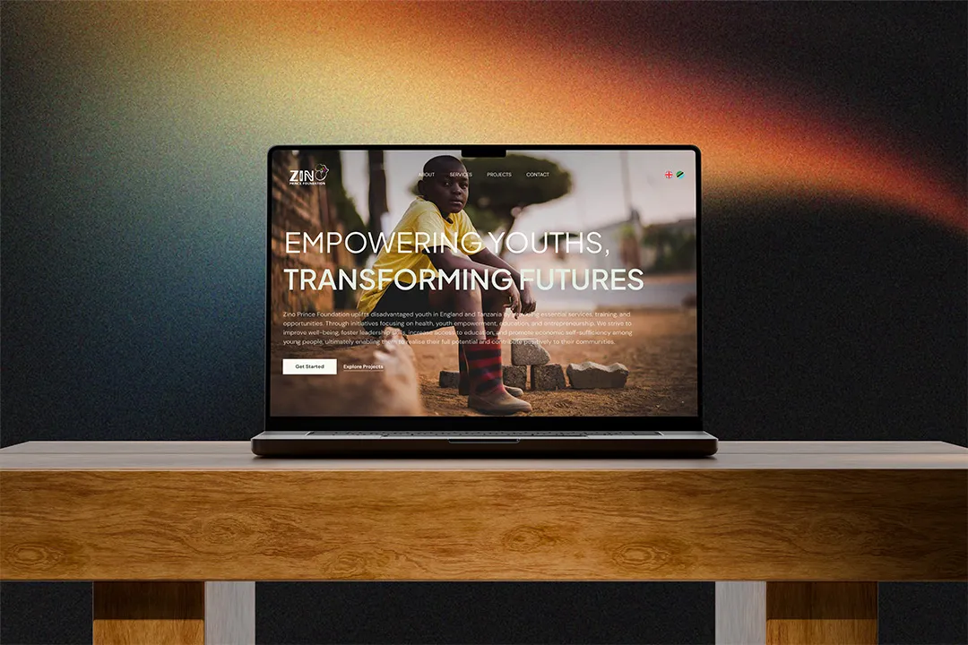 A MacBook on a wooden table top showcasing Zino Prince Foundation Website